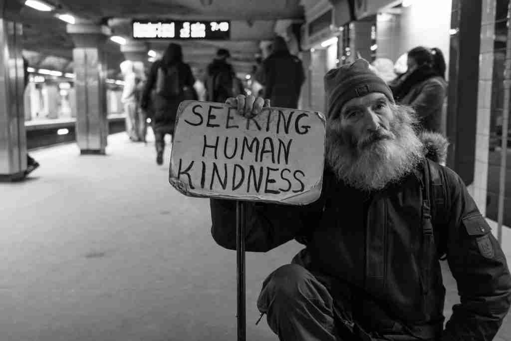 Homeless Person with sign "Seeking  Human Kindness"